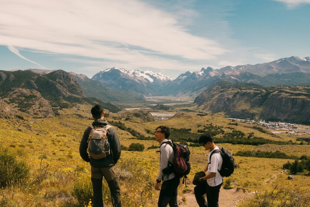 Group of happy travelers with backpacks exploring a beautiful mountain landscape together